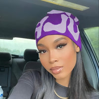 This image shows a woman wearing a purple mea culpa beanie.
